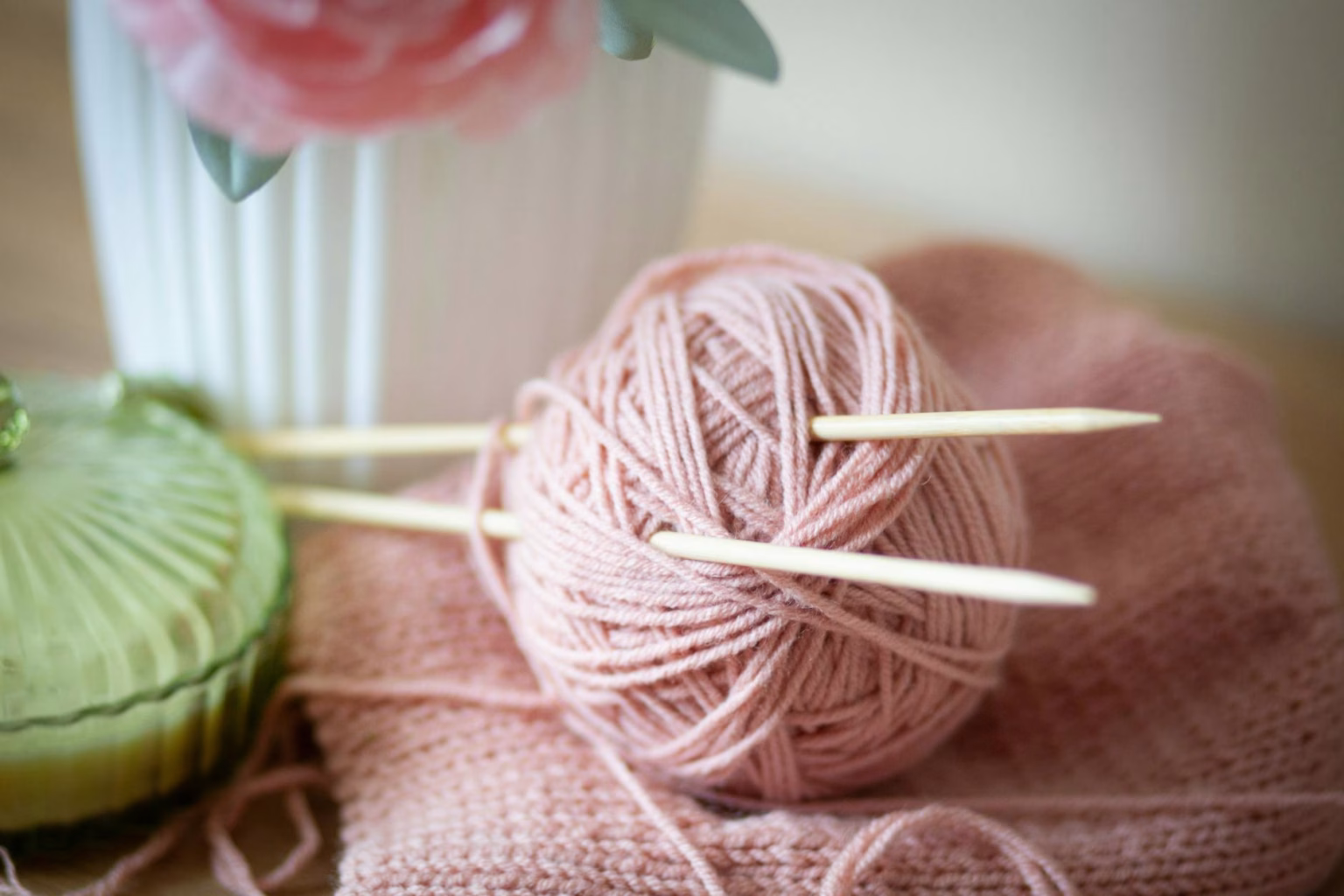 a pink ball of yarn and knitting needles