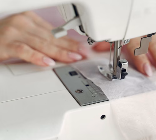 person sewing with a white sewing machine