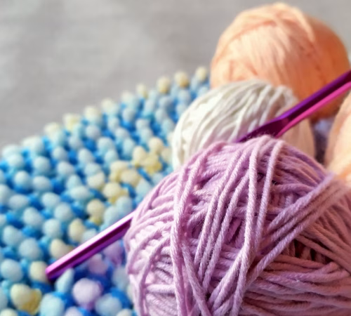 close up photo of a crochet hook and colorful yarns