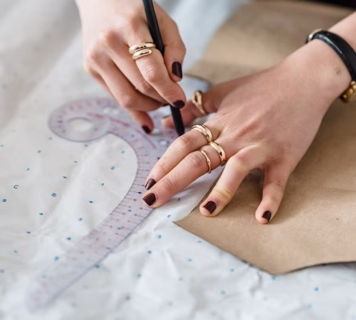 crop seamstress drawing on paper with sewing pattern and ruler